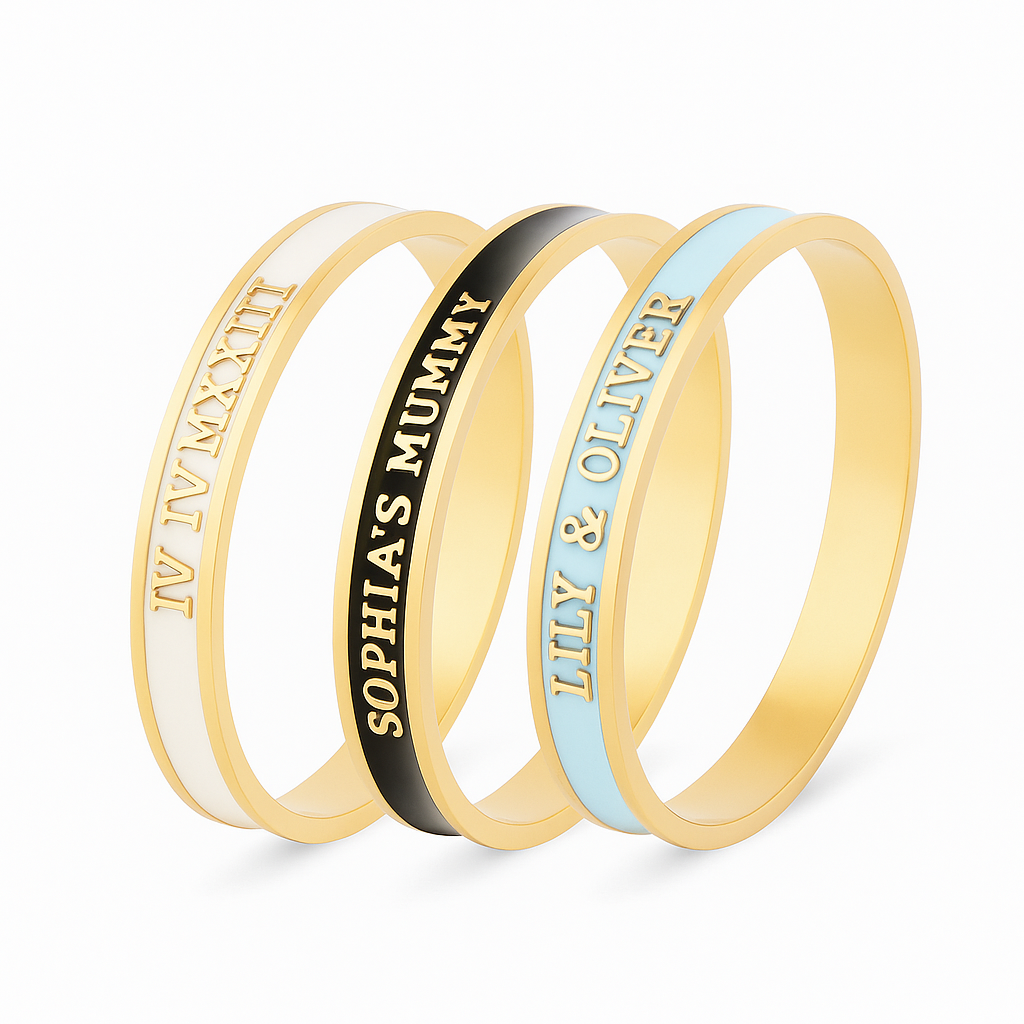 3 enamel bangles with different customised text on a white background. White and gold bangle reads 'IV IV MXXIII', black and gold bangle reads 'Sophia's Mummy', pale blue and gold bangle reads 'Lily & Oliver'